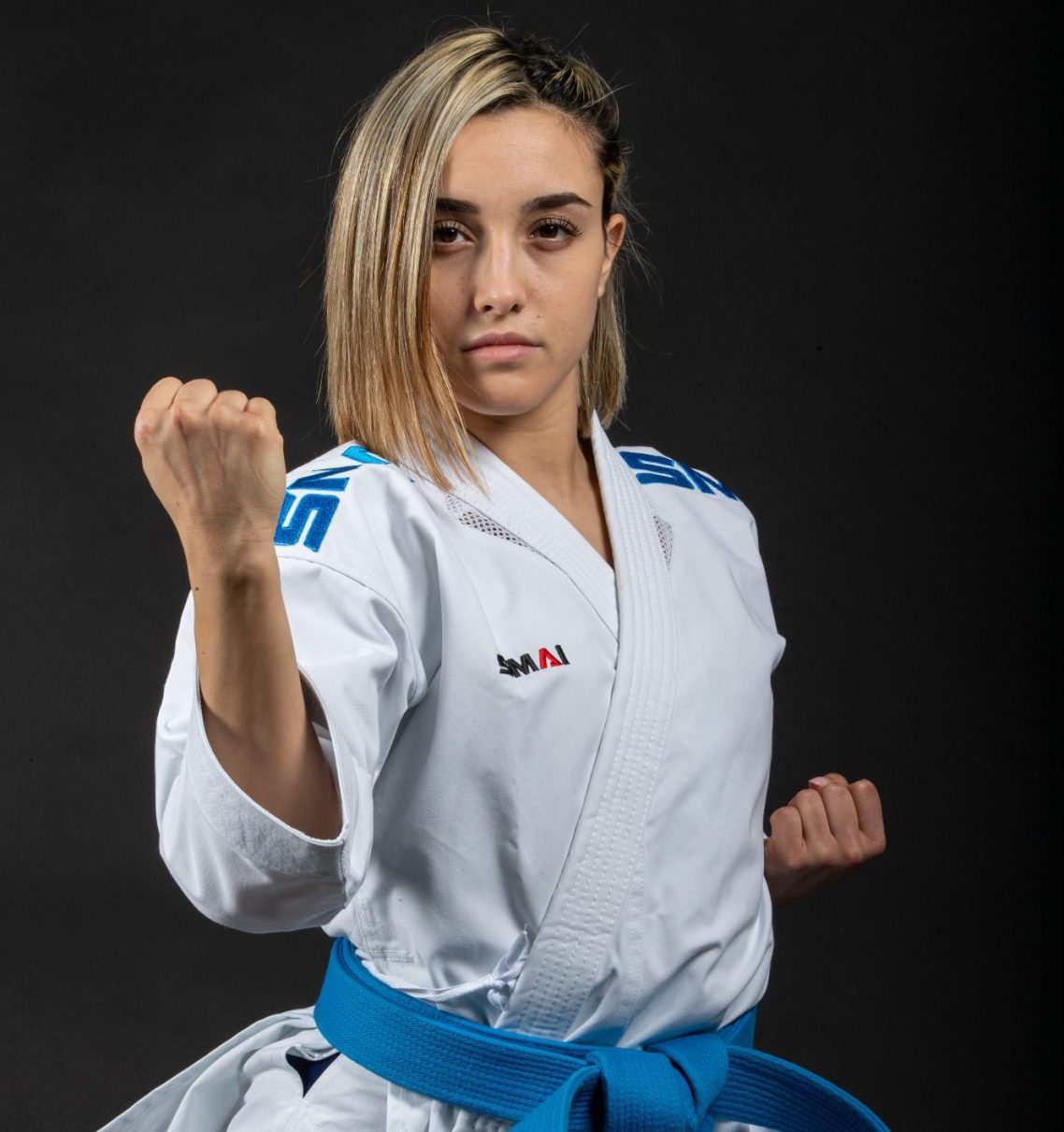 Kaminari X Karateka in Kaminari X Gi mit blauer Gürtelschärfe, zeigt eine Kampfhaltung.